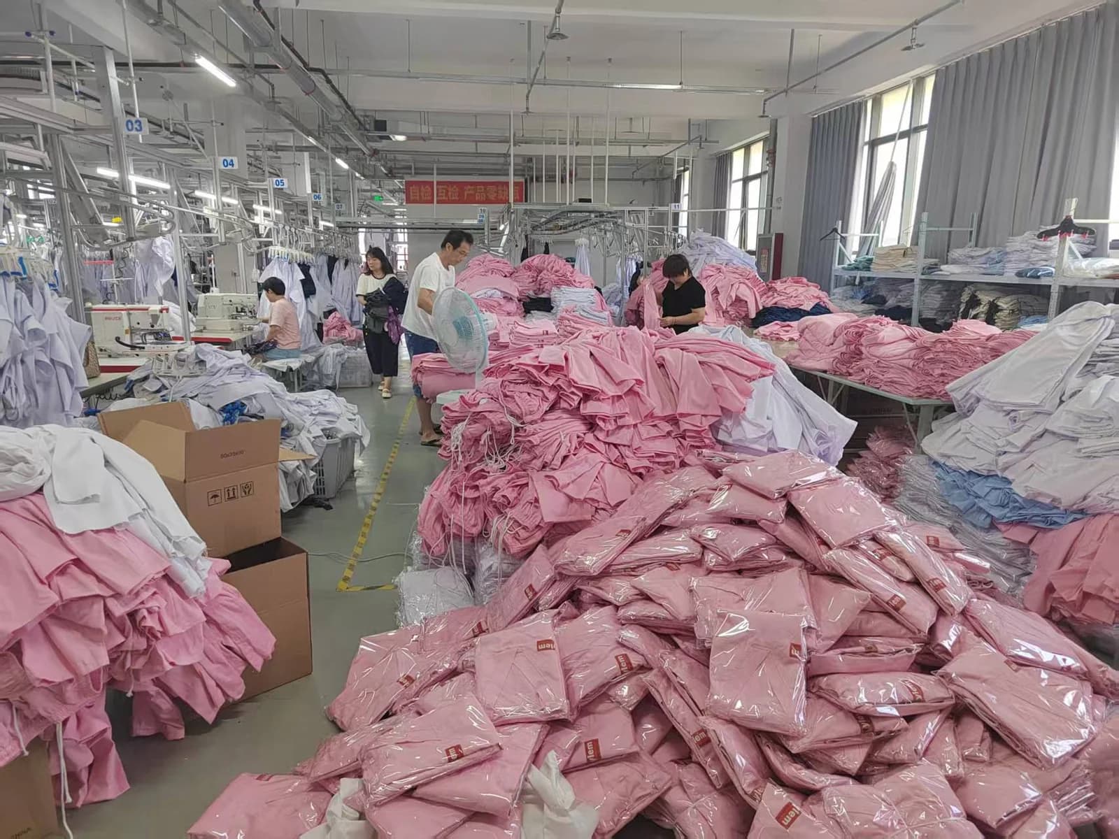 Individually packed pink garments beside garment sorting tables