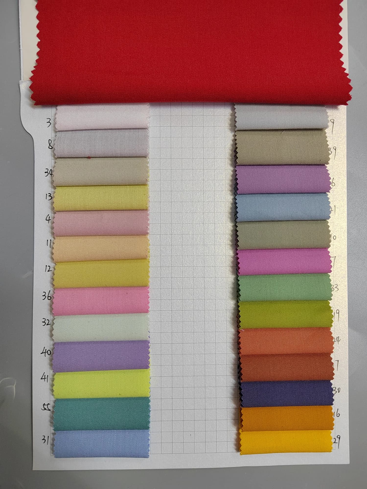 Fabric color card with pastel and bright swatches beneath a larger red fabric sample
