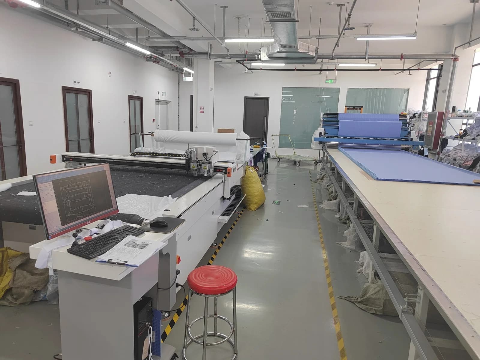 Fabric spreading and cutting equipment in the medical uniform production photo supplied by Raise
